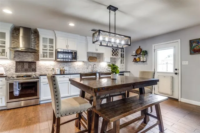 a kitchen with stainless steel appliances a dining table chairs stove and refrigerator