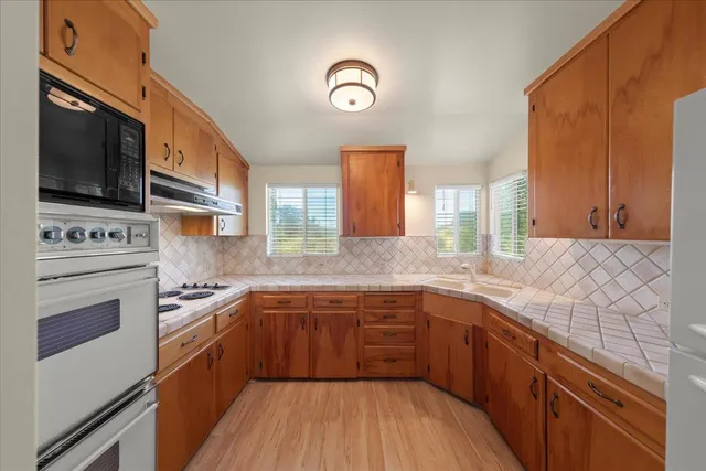 a kitchen with stainless steel appliances granite countertop a sink stove and microwave