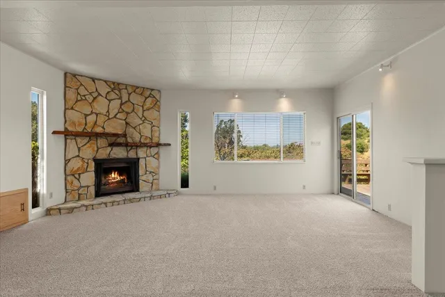 an empty room with windows and fireplace