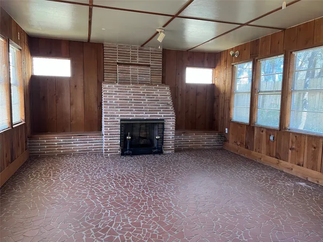 an empty room with windows and fireplace