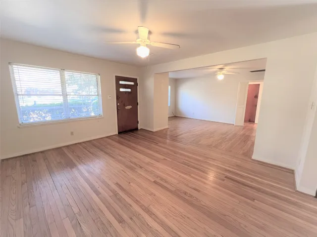 a view of an empty room with wooden floor and a window