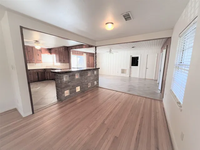 a living room with stainless steel appliances furniture and a wooden floor
