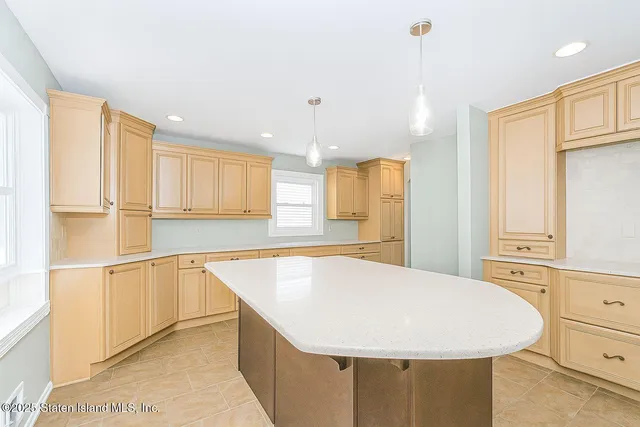 a room with stainless steel appliances kitchen island granite countertop a sink a refrigerator and white cabinets with wooden floor