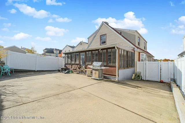 a view of a white house with a small yard and wooden fence