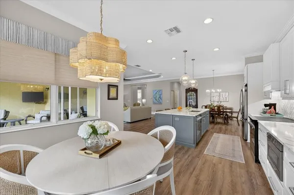 a large kitchen with kitchen island a stove a sink a dining table and chairs with wooden floor