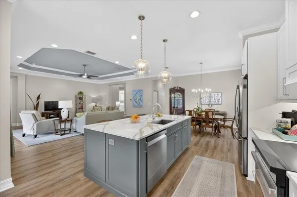 a kitchen with stainless steel appliances granite countertop a refrigerator a stove a sink a dining table and chairs with the outer view