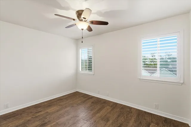 an empty room with wooden floor closet and windows