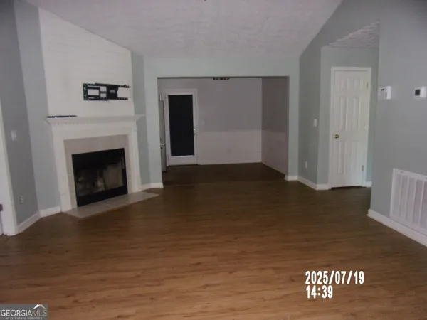 a view of a livingroom with wooden floor and a fireplace