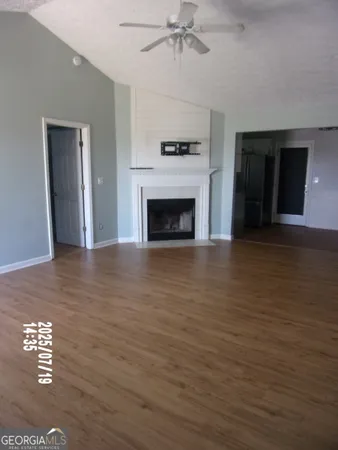 an empty room with wooden floor fireplace and windows