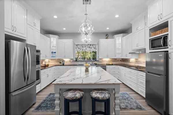 a kitchen with stainless steel appliances granite countertop a refrigerator a stove and a sink