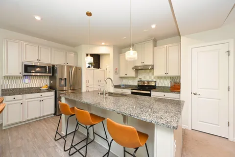 a kitchen with stainless steel appliances granite countertop a stove top oven a sink refrigerator and white cabinets