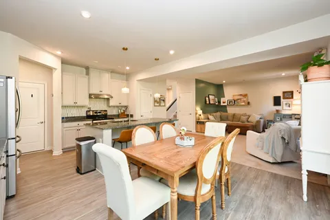 a dining room with stainless steel appliances granite countertop a table chairs and a refrigerator