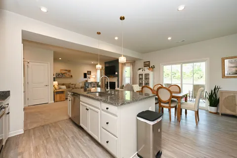 a kitchen with granite countertop a stove and white cabinets with wooden floor