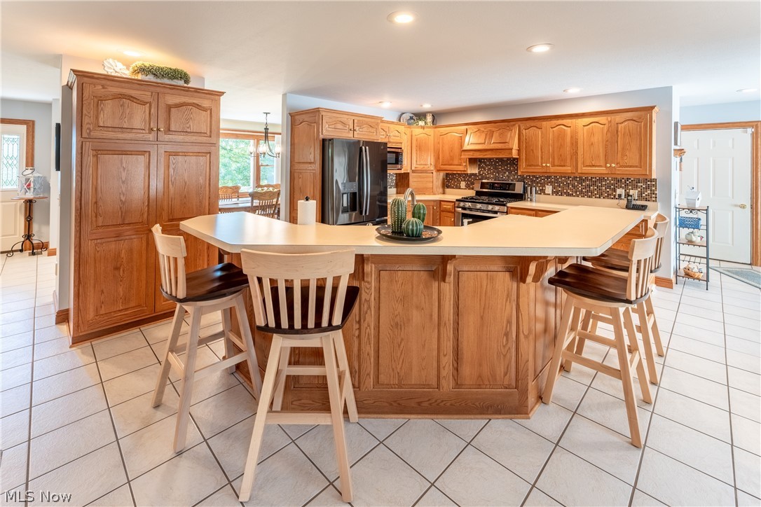 20 Reedsburg Road Wooster, OH 44691 - Photo 11 of 42 Kitchen with stainless steel appliances, custom range hood, backsplash, light tile floors, and a breakfast bar