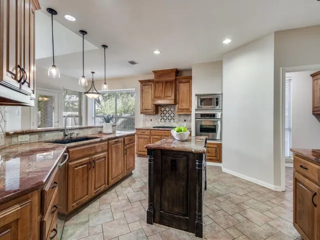 a kitchen with kitchen island granite countertop a sink counter top space appliances and cabinets