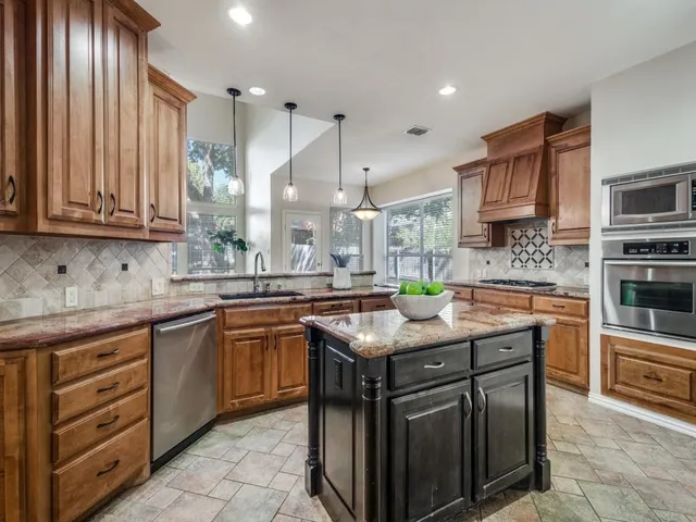a kitchen with stainless steel appliances granite countertop a sink stove and cabinets