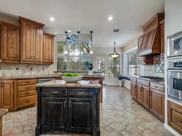 a kitchen with stainless steel appliances granite countertop a stove a sink and a refrigerator