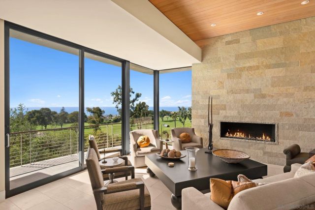 a living room with furniture a fireplace and a floor to ceiling window