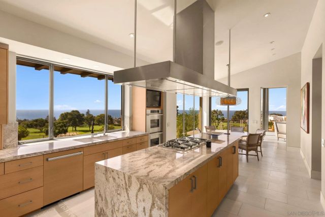 a large kitchen with kitchen island a large window a sink and cabinets