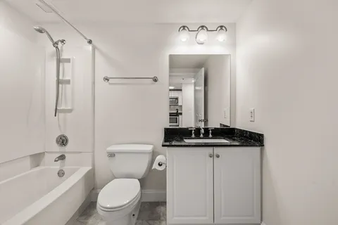 a bathroom with a granite countertop sink a toilet and shower