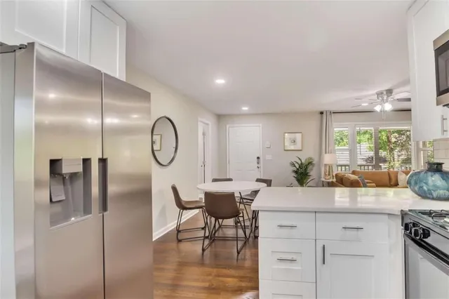 a kitchen with stainless steel appliances granite countertop a stove a sink a dining table and chairs with wooden floor