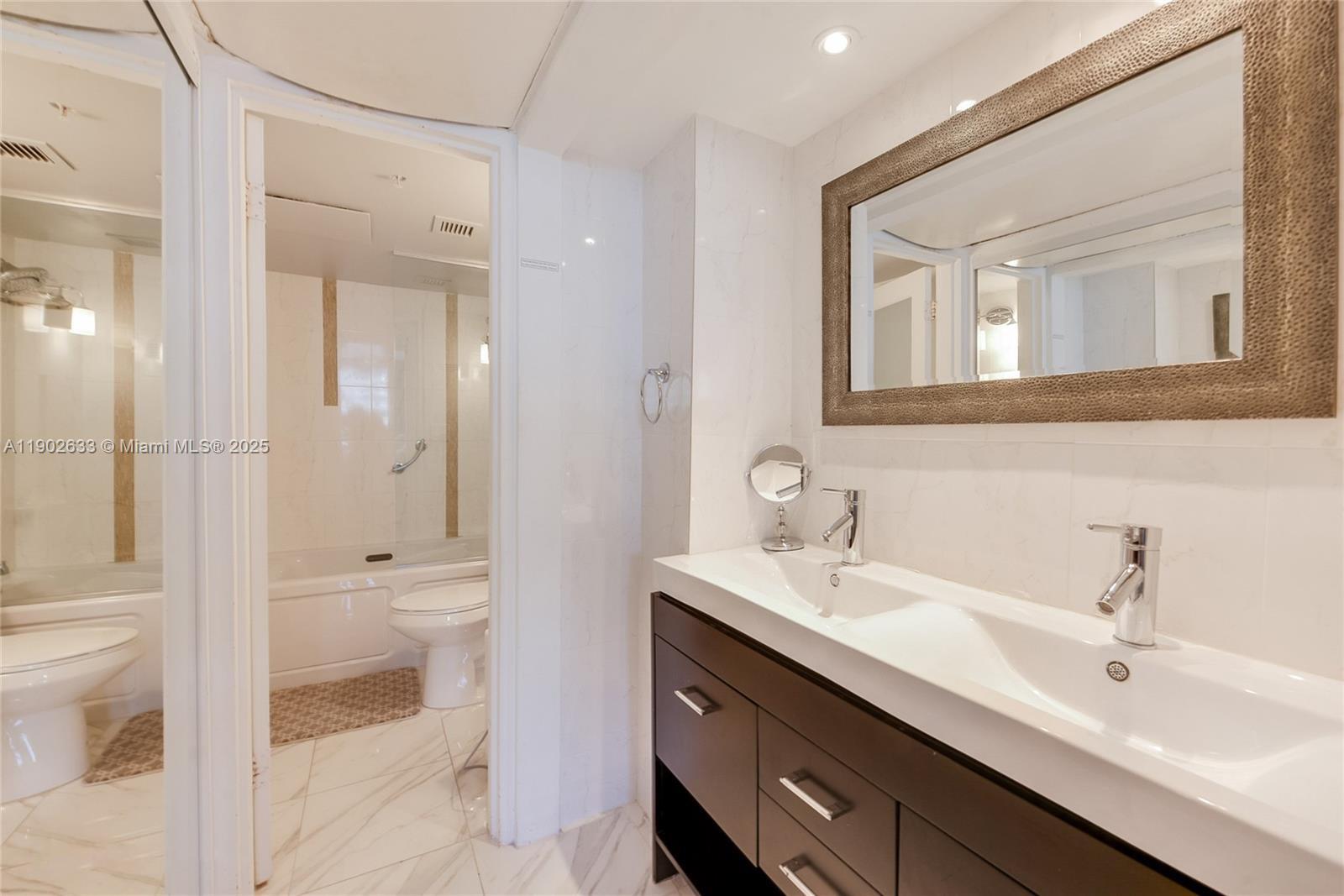 1500 Bay Road, Unit 846S Miami Beach, FL 33139 - Photo 12 of 40 a bathroom with a toilet a sink a mirror and a shower