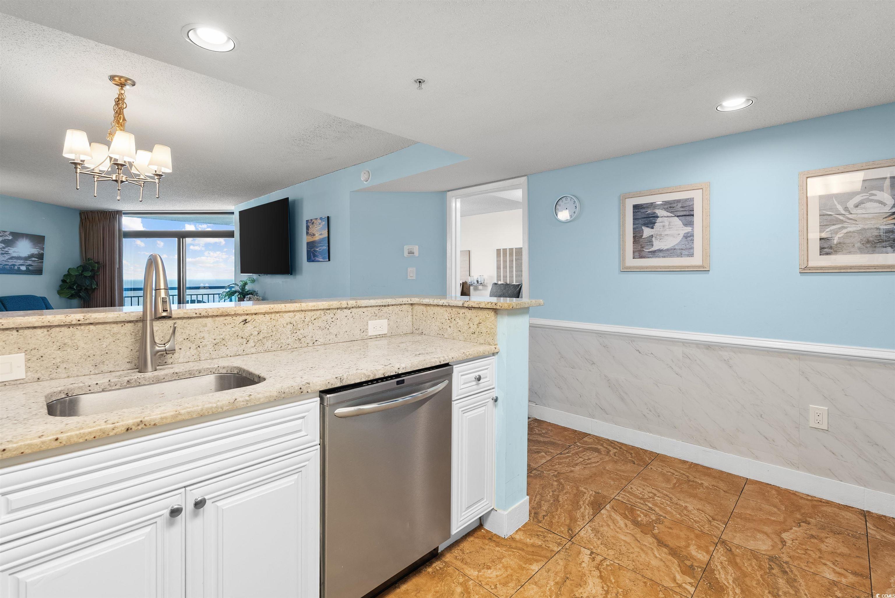 205 74th Avenue North, Unit 1908 Myrtle Beach, SC 29572 - Photo 11 of 39 Kitchen with white cabinets, light stone counters, dishwasher, wainscoting, and a chandelier