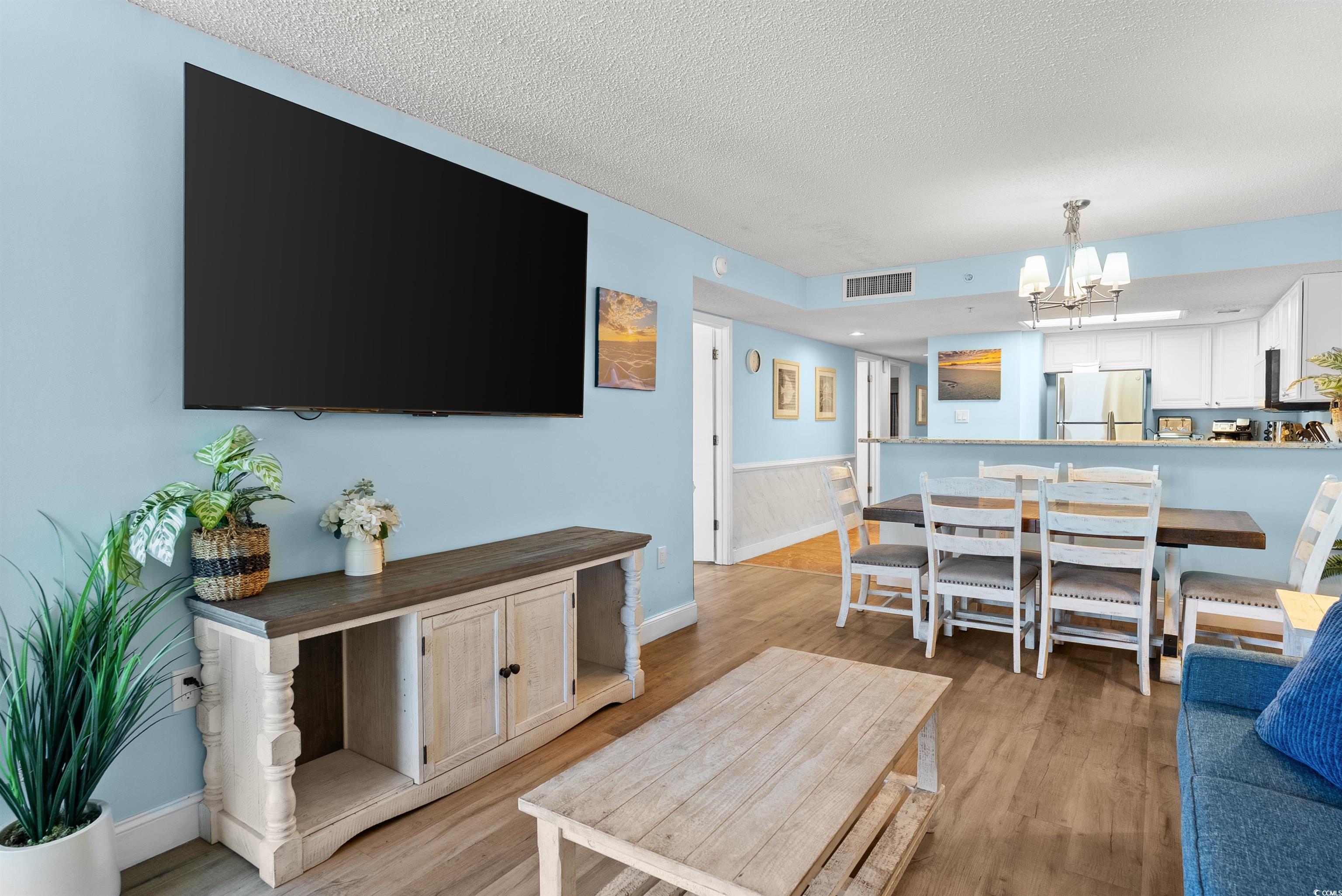 205 74th Avenue North, Unit 1908 Myrtle Beach, SC 29572 - Photo 18 of 39 Living room with wainscoting, light wood-style floors, a textured ceiling, and a chandelier