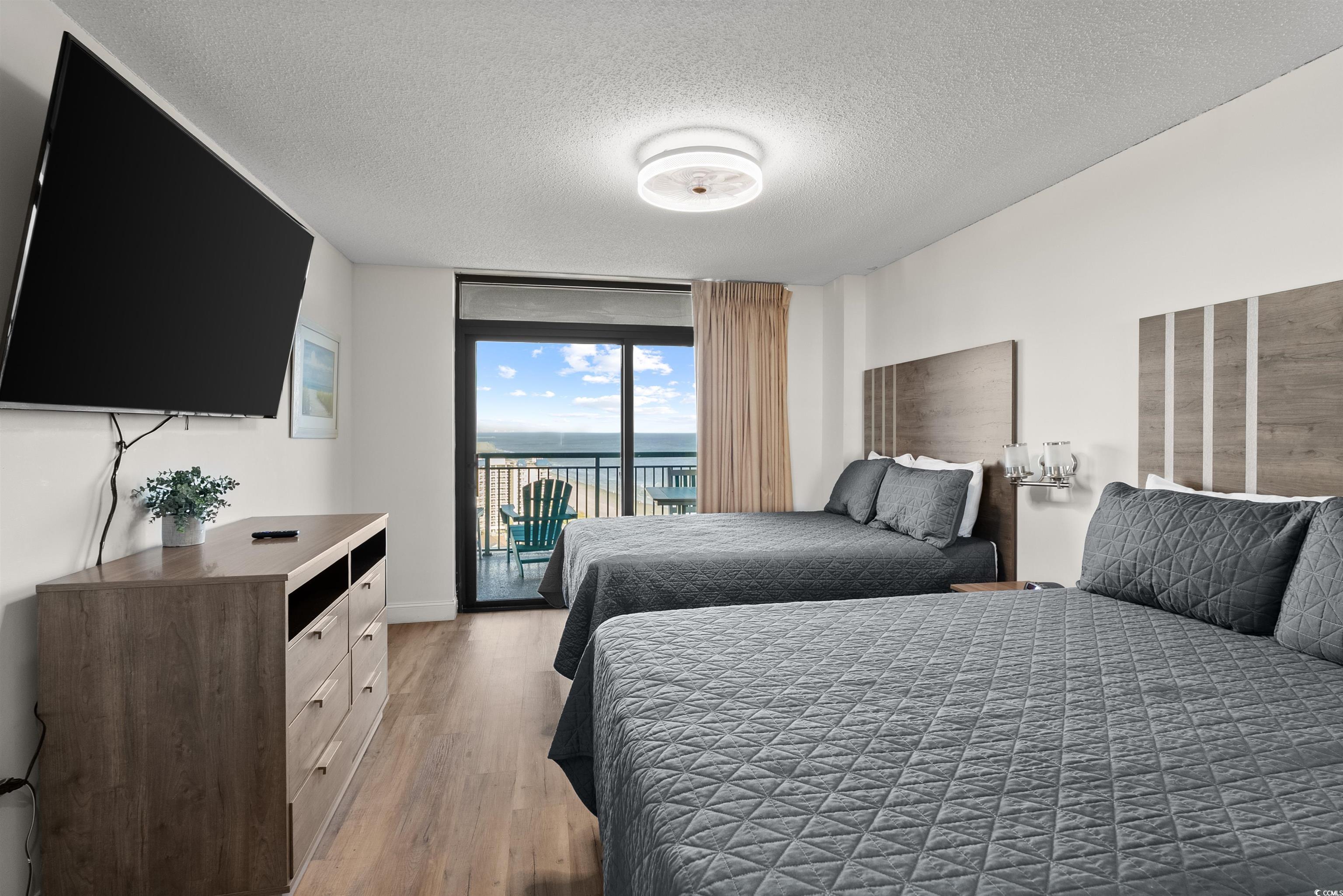 205 74th Avenue North, Unit 1908 Myrtle Beach, SC 29572 - Photo 21 of 39 Bedroom featuring a textured ceiling, access to outside, a water view, light wood finished floors, and a wall of windows