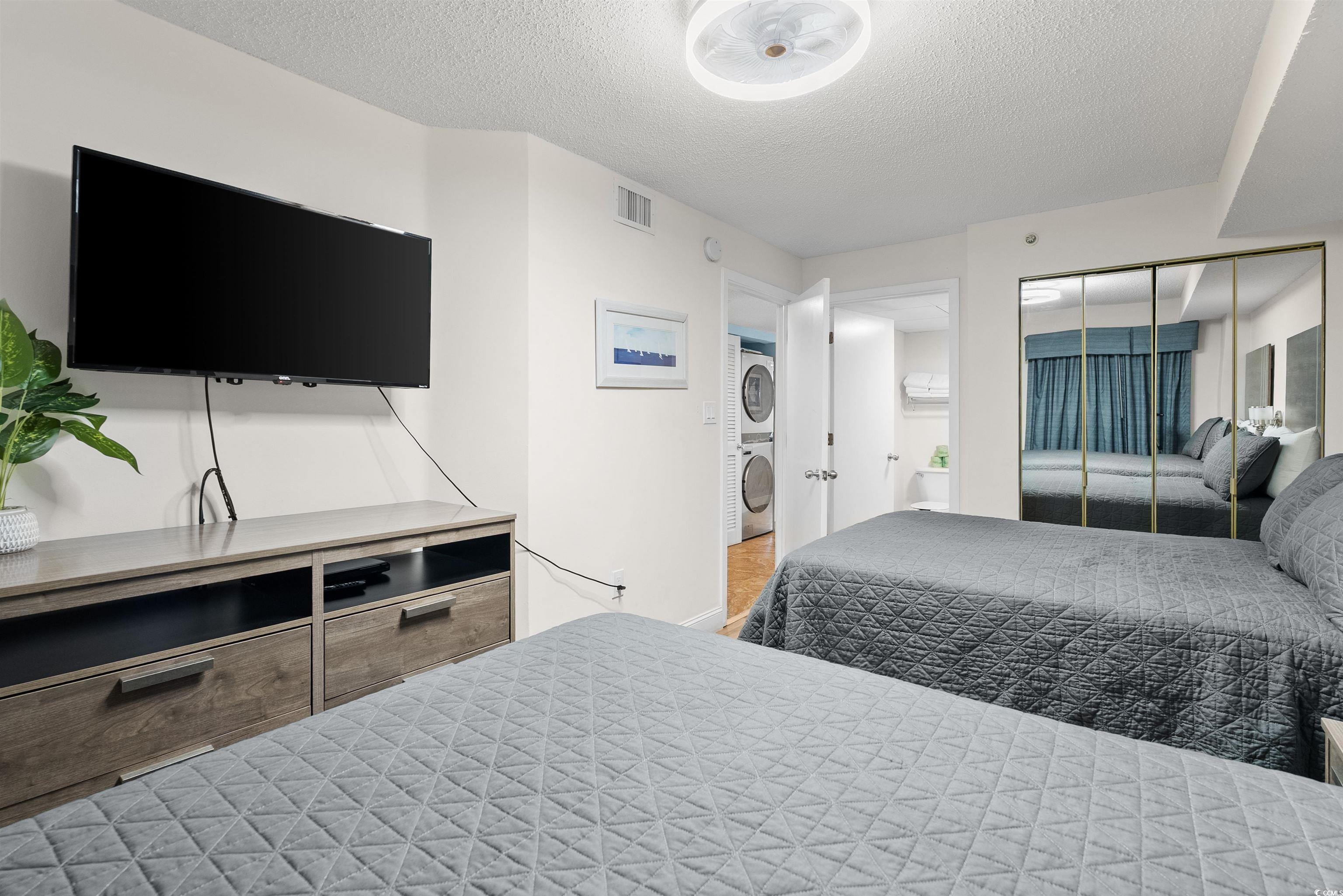 205 74th Avenue North, Unit 1908 Myrtle Beach, SC 29572 - Photo 25 of 39 Bedroom with a textured ceiling, stacked washer / drying machine, a closet, and ensuite bathroom