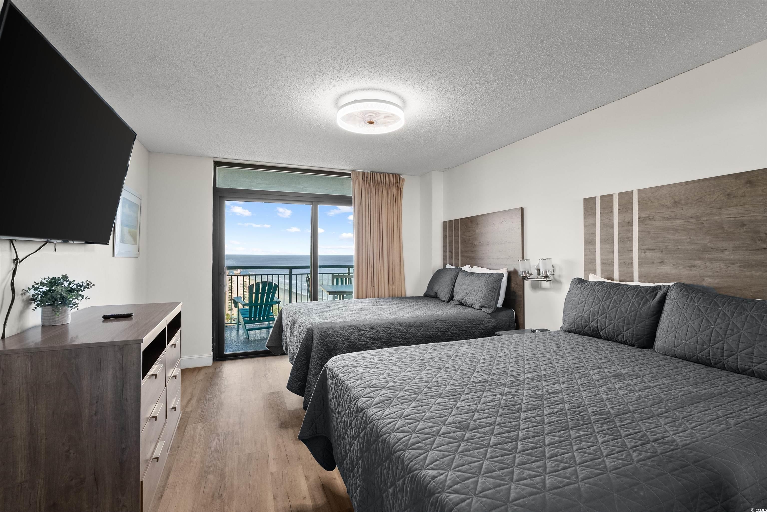 205 74th Avenue North, Unit 1908 Myrtle Beach, SC 29572 - Photo 26 of 39 Bedroom featuring a textured ceiling, access to exterior, expansive windows, a water view, and light wood finished floors