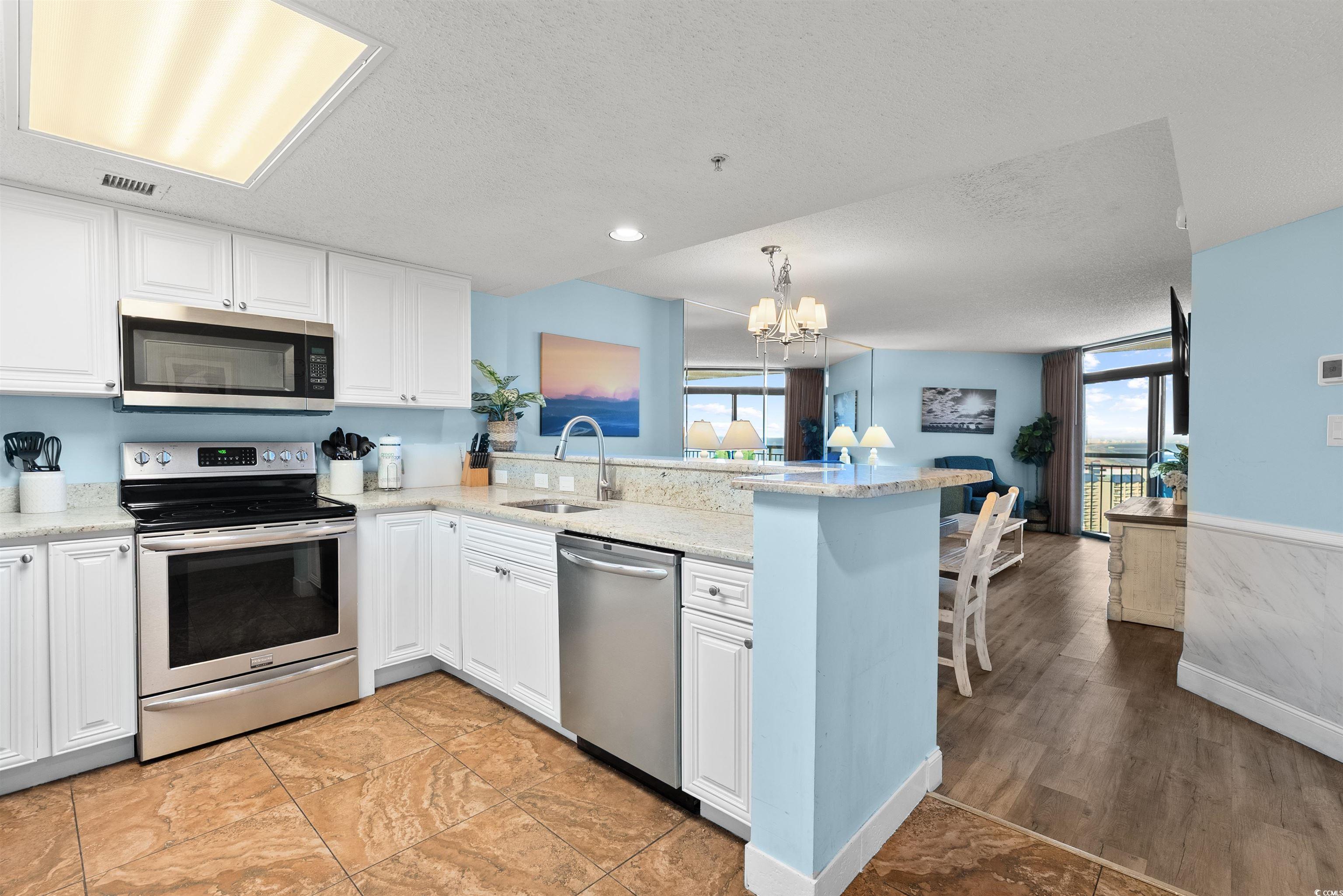 205 74th Avenue North, Unit 1908 Myrtle Beach, SC 29572 - Photo 9 of 39 Kitchen featuring stainless steel appliances, white cabinetry, light stone counters, a chandelier, and healthy amount of natural light