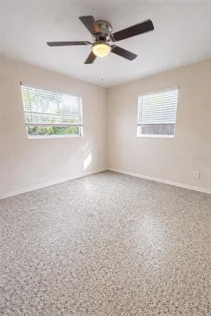 an empty room with windows and fan