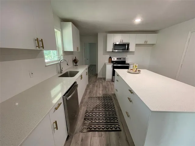 a kitchen with sink a microwave and cabinets
