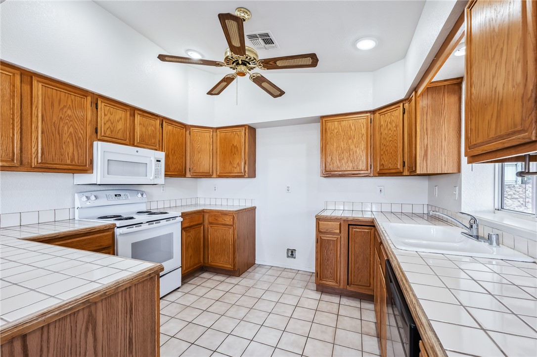 2524 South Ridge Avenue Bullhead City, AZ 86429 - Photo 20 of 64 Kitchen with white appliances, tile countertops, and brown cabinets