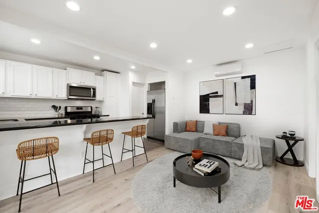 a living room with furniture a flat screen tv and kitchen view
