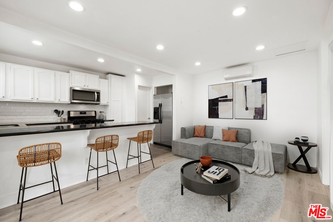 a living room with furniture a flat screen tv and kitchen view
