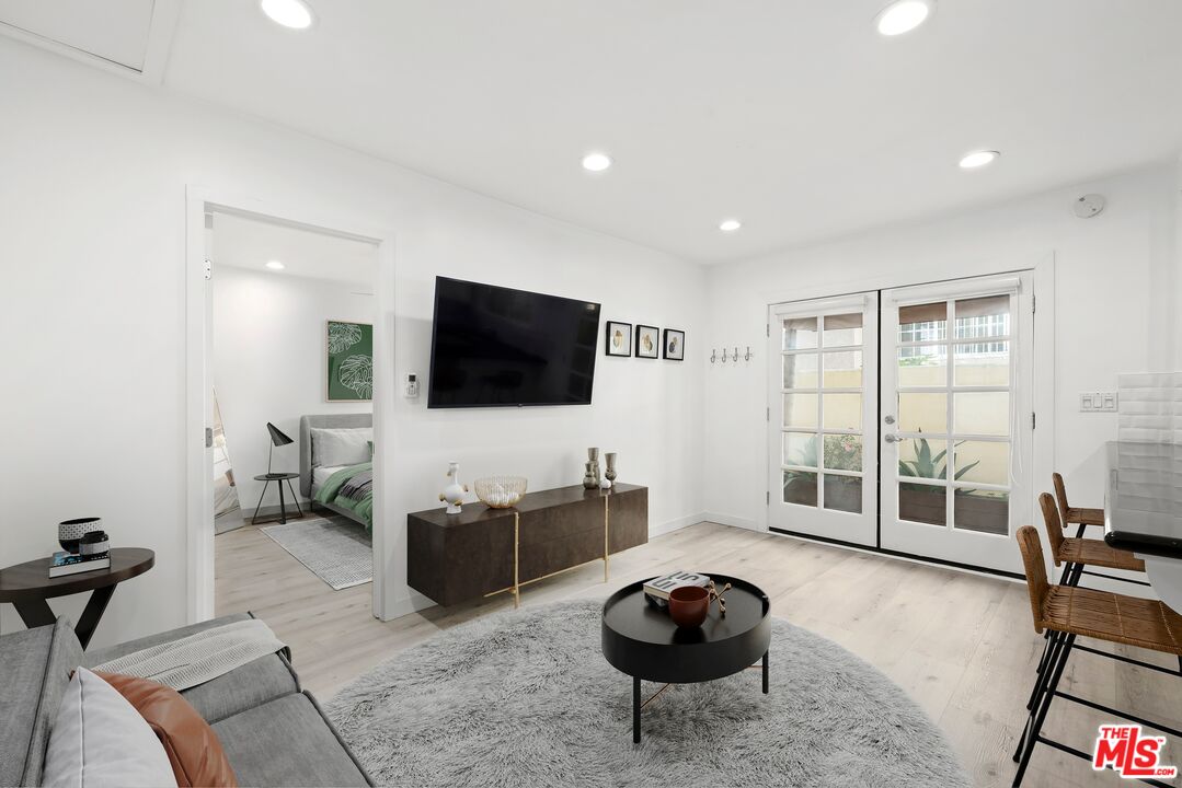 927 Euclid Street, Unit B Santa Monica, CA 90403 - Photo 2 of 8 a living room with furniture a flat screen tv and a floor to ceiling window