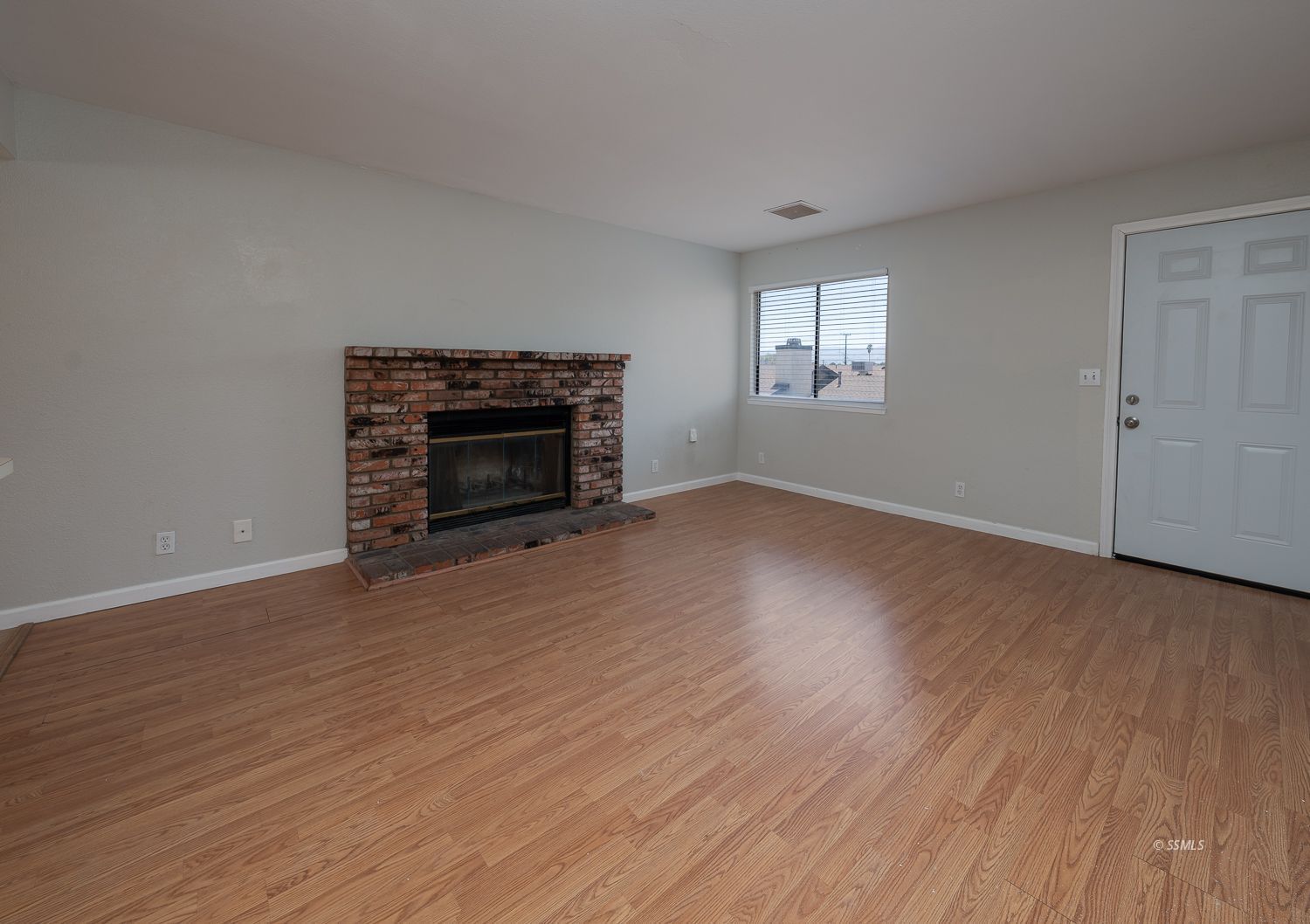 429 South Sunset Street Ridgecrest, CA 93555 - Photo 4 of 15 an empty room with wooden floor fireplace and windows