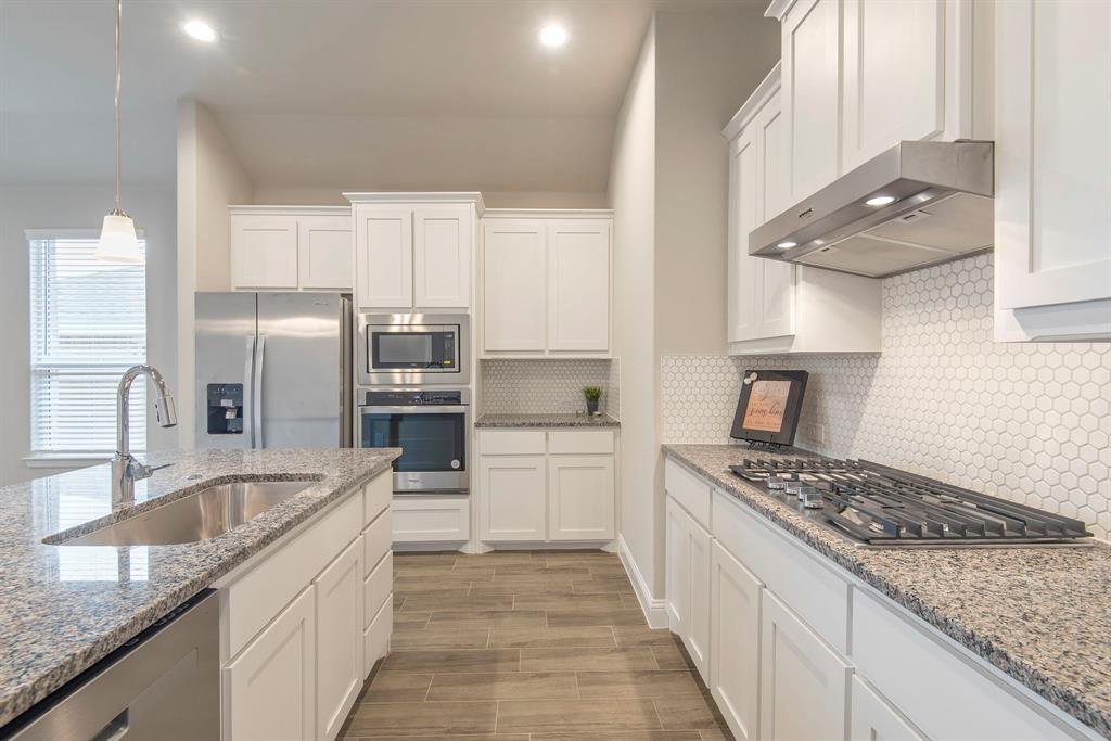 2301 Ruff Road Denton, TX 76205 - Photo 8 of 23 Kitchen featuring white shaker-style cabinetry, granite countertops, stainless steel appliances, a gas range with an overhead vent hood, and a white penny tile backsplash