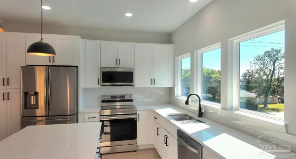 a kitchen filled with stainless steel appliances granite countertop a stove a sink and a refrigerator with wooden floor