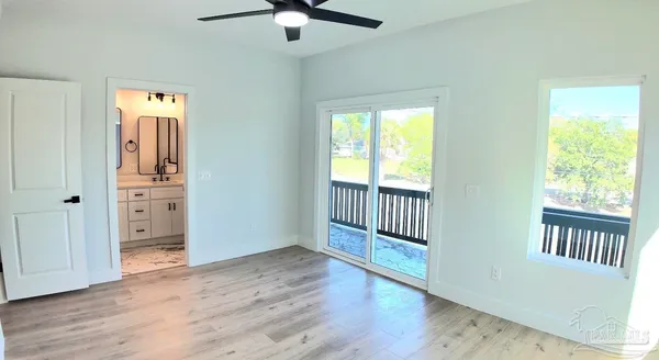 an empty room with wooden floor fan and windows