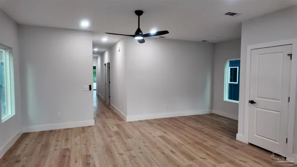 an empty room with wooden floor closet and windows