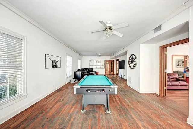 a room with wooden floor pool table and windows
