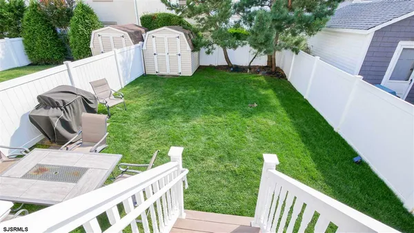 a view of backyard with white fence and trees