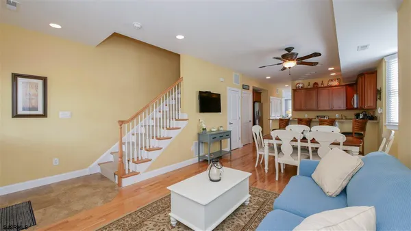 a living room with furniture kitchen view and a wooden floor