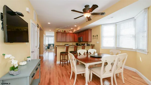 a dining room with stainless steel appliances kitchen island granite countertop a table chairs and a refrigerator