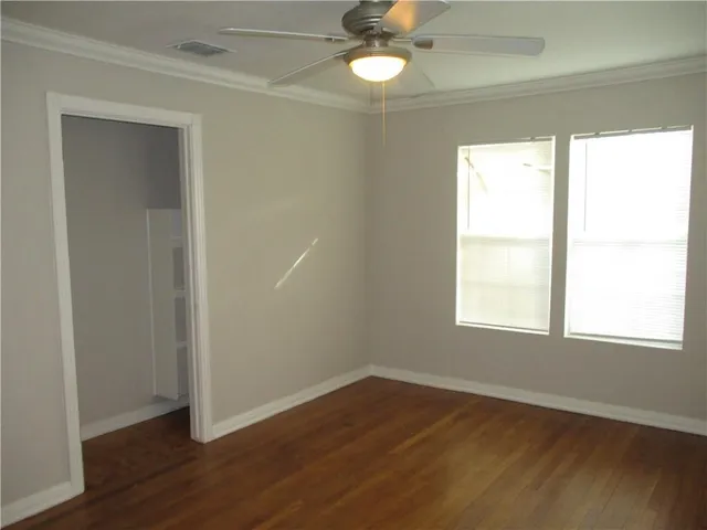 an empty room with wooden floor closet and windows