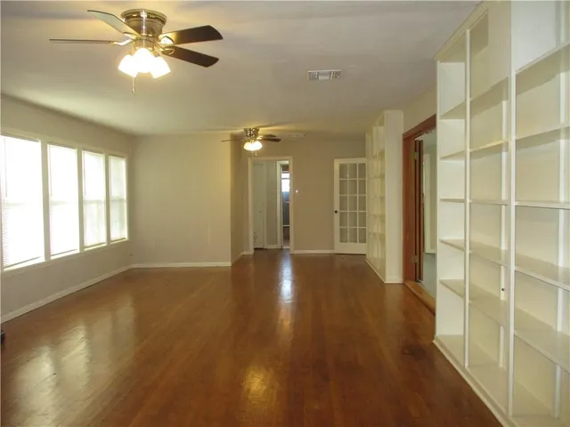a view of an empty room with window and wooden floor