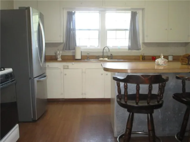 a kitchen with stainless steel appliances granite countertop a kitchen island a sink a window and a refrigerator